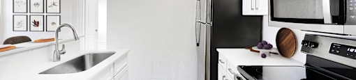 a kitchen with white cabinetry and black appliances  at Hayden on West Ave, San Antonio
