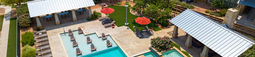an aerial view of a resort style pool with lounge chairs and umbrellas