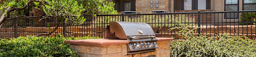 an outdoor barbecue grill with a stone countertop in front of an apartment building