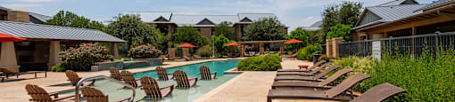 a pool with lounge chairs and umbrellas at the whispering winds apartments in pearland,
