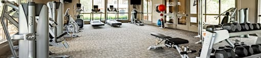 a spacious fitness center with cardio equipment and windows