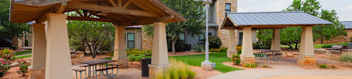 a picnic area with picnic tables and umbrellas at the whispering winds apartments in pearland