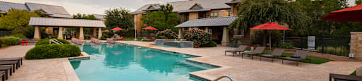 a swimming pool with lounge chairs and umbrellas in front of a building