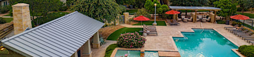 an aerial view of a resort style swimming pool with lounge chairs and umbrellas