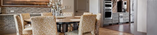 a dining area with a wooden table and chairs and a brick wall with a painting on it