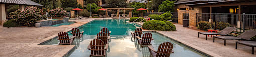 a swimming pool with chairs and umbrellas in front of a house