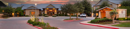 a building with a parking lot in front of it with a sunset in the sky