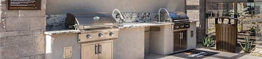 A modern outdoor kitchen area with a grill and sink.