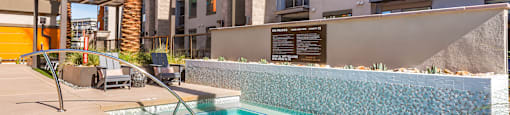 A pool surrounded by a stone wall and palm trees.