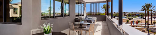 A patio with a table and chairs overlooking a parking lot.