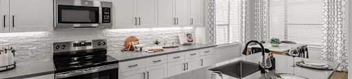 A modern kitchen with a black countertop and white cabinets.