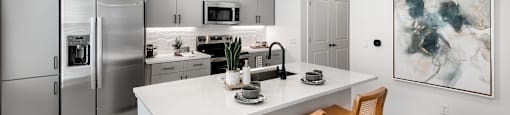 A modern kitchen with a white countertop and stainless steel appliances.