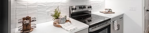 A modern kitchen with white cabinets and a black refrigerator.