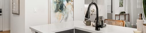 A modern kitchen with a large painting on the wall above the sink.