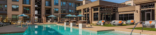 A large swimming pool in front of a building with a clear blue sky above.