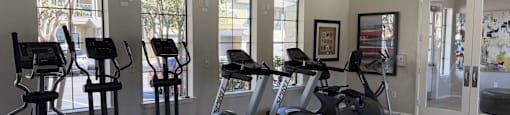 A spacious gym with a variety of exercise equipment and a ceiling fan.