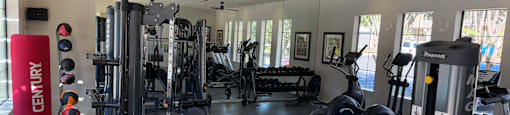 A gym with a variety of equipment including treadmills, weights, and exercise machines.