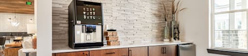 a kitchen with a coffee maker on a counter and a brick wall