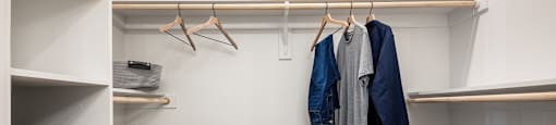 a walk in closet with white walls and wood floors