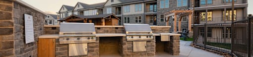 an outdoor kitchen with a grill and a building in the background