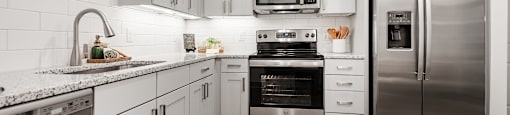 a kitchen with white cabinets and stainless steel appliances