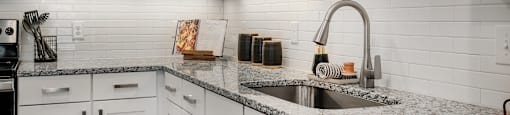 a kitchen with white cabinets and granite counter tops and a sink