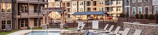 a swimming pool with lounge chairs in front of an apartment building