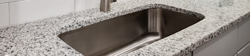 a stainless steel sink in a granite counter top in a kitchen