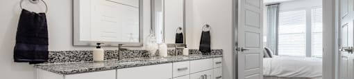 a bathroom with two sinks and mirrors and a door to a bedroom