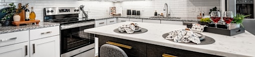 a kitchen with white cabinets and a large island with two chairs