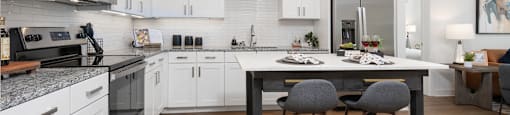 a kitchen with white cabinets and an island with three chairs