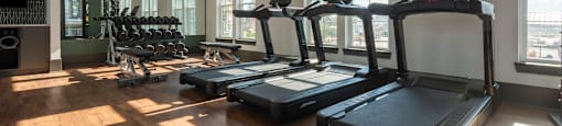 a gym with treadmills and other exercise equipment in a building with large windows