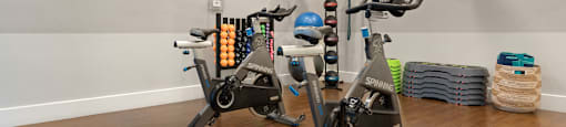 a room with two exercise bikes and a tv on the wall