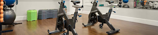 a spacious fitness room with cardio equipment and a flat screen tv