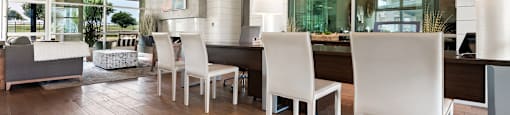 a dining area with a long wooden table and white chairs