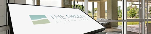 the green at brainerd logo on a table in front of a glass door