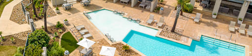 an aerial view of the resort style pool with lounge chairs and tables