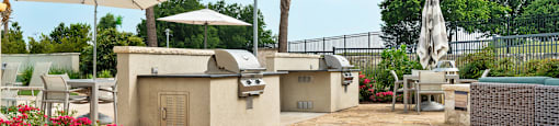 a patio with bbq grills and umbrellas at the enclave at woodbridge
