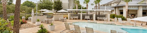 a resort style pool with lounge chairs and umbrellas