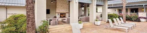 a patio with lounge chairs and a fire pit
