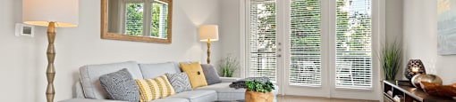 a living room with white walls and a white couch with yellow and gray pillows