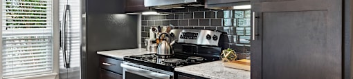 a kitchen with dark cabinets and white countertops