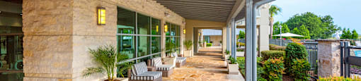 a covered walkway with benches and potted plants