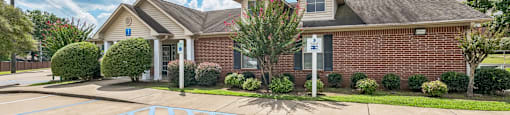 an empty parking lot in front of a brick house