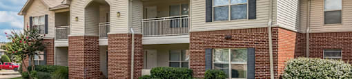 the outlook of a brick and mortar apartment building with a green lawn
