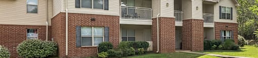 the outlook of a brick and white apartment building with a green lawn