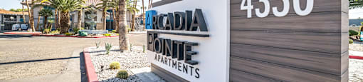 a sign that reads accadia pointe apartments in front of a building with palm