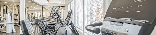 a gym with treadmills and other exercise equipment in a building with large windows