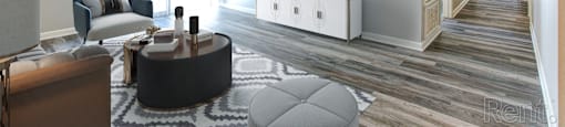 A living room with a grey ottoman and a white cabinet with a flat screen TV on top.