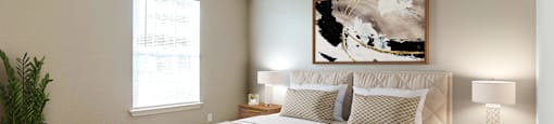 A bedroom with a large bed, a potted plant, and a painting on the wall.